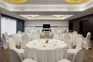 迪拜Hyatt Place Dubai Jumeirah的一间会议室,配有白色的桌椅和屏幕