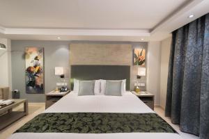 马斯喀特阿曼森特马斯喀特酒店的卧室配有一张带两张桌子的大型白色床