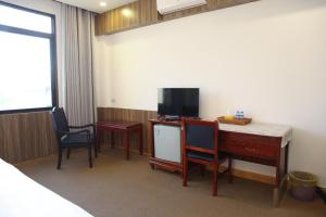 芒赛Mittaphap Hotel Oudomxai的客房设有一张桌子、两把椅子和一台电视