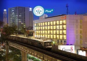 曼谷Grand 5 Hotel & Plaza Sukhumvit Bangkok的一座有建筑物的城市里轨道上的火车