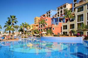 阿德耶Bahia Principe Sunlight Tenerife - All Inclusive的棕榈树和建筑度假村的游泳池