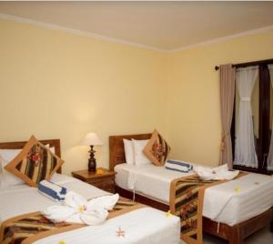 乌布Buana Ubud Inn的酒店客房,配有三张带鲜花的床