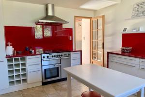 Bailleau-lʼÉvêqueMagnificent 17th property calm and relaxation的红色的厨房配有炉灶和桌子