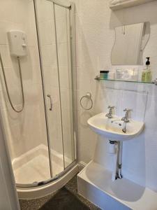 斯卡伯勒Hermosa Guest House的带淋浴和盥洗盆的白色浴室