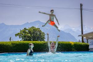 因特拉肯Camping Lazy Rancho - Eiger - Mönch - Jungfrau - Interlaken的男孩和女孩一起跳进游泳池