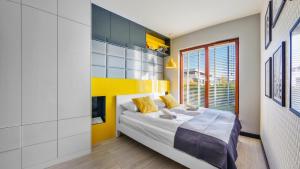 格丁尼亚Apartamenty Sun & Snow Gdynia Nowe Orłowo的一间卧室设有一张床和黄色的墙壁