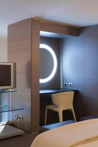 卡利亚里UNAHOTELS T Hotel Cagliari的一间卧室配有一张床、一把椅子和电视。