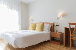 卢戈Hostal ALBA Lugo的卧室配有一张带黄色枕头的大型白色床。