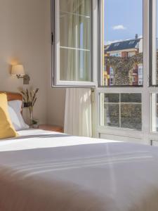 卢戈Hostal ALBA Lugo的一间卧室设有一张床和两个大窗户