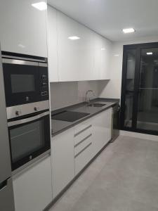 PaiportaModern & sunny apartment near Valencia的厨房配有白色橱柜和黑色家电