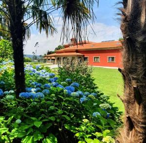 维拉诺瓦-德法马利Villam Natura & Spa的一座花园,在一座建筑前方,鲜花盛开