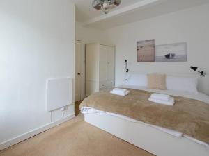 北贝里克Pebbles Apartment的白色卧室配有一张大床和两条毛巾