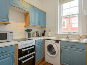 北贝里克Pebbles Apartment的厨房配有蓝色橱柜和洗衣机。
