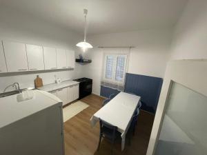 图兰杰Holiday house Fila的厨房配有白色橱柜、桌子和水槽。