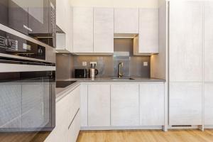 伦敦LuxLet Apartments - Heart of Hampstead, London的厨房配有白色橱柜和水槽
