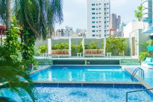 巴兰基亚Country International Hotel的棕榈树建筑屋顶上的游泳池
