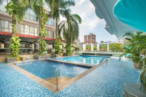 巴兰基亚Country International Hotel的棕榈树建筑中间的游泳池
