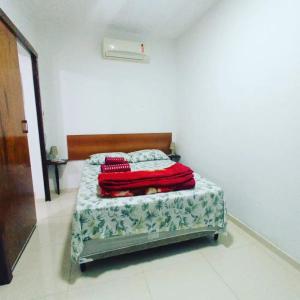 里约热内卢Casa Oliveira's Paquetá的一间卧室配有一张床铺,床上铺有红色毯子