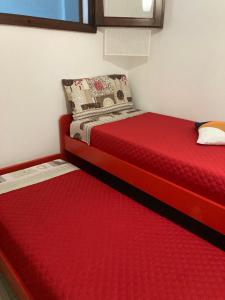 特乌拉达al Sulcis 35的一间卧室设有两张带红色床单的床和窗户。