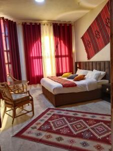 瓦迪穆萨Petra fort hotel的一间卧室配有两张床、椅子和红色窗帘