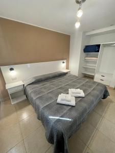 特雷斯阿罗约斯Hermoso y cómodo dpto c/cochera Tres Arroyos的一间卧室配有一张大床和两条毛巾