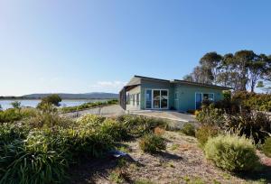 Bream CreekWaterfront 'Jemadda' Family Lodge的湖畔的蓝色小房子