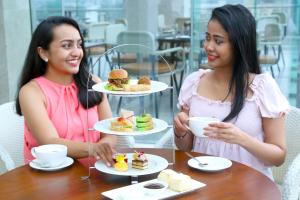 科伦坡Courtyard by Marriott Colombo的两个坐在餐桌上,配上食物盘的女人