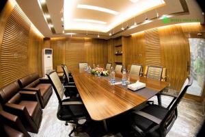 达卡Hotel Shuktara Dhaka的一间会议室,配有长木桌子和椅子