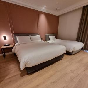 釜山Busan City Hotel的酒店客房,配有两张带白色床单的床