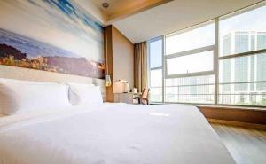 济南济南高新万达广场天辰路亚朵酒店的卧室设有一张白色大床和大窗户
