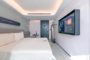 上海上海陆家嘴第一八佰伴轻居酒店的卧室配有一张床,墙上配有电视。