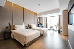 成都成都太古里未来中心亚朵酒店的酒店客房设有两张床和一张桌子。