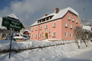 Ardning多夫维特酒店的一座大粉色的建筑,在雪中标有标志
