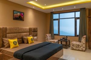 西姆拉The Hosteller Shimla的一间卧室配有一张床、两把椅子和一个窗户
