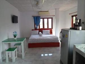 万象Ban Saylomleng Residence的一间卧室配有一张床铺、一张桌子和一台冰箱