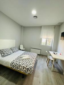 马德里HOSPEDAJE CUATRO VIENTOS的一间卧室配有一张床、一张桌子和一张书桌