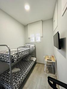 马德里HOSPEDAJE CUATRO VIENTOS的小房间设有两张双层床和一张桌子