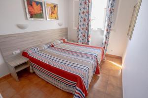 阿雷纳尔登卡斯特尔Seth Sa Mirada的一张床上的房间,上面有条纹毯子