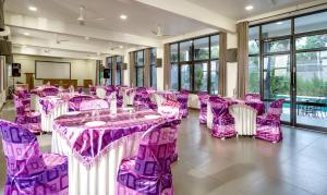玛纳多迪Fern Tree Resort的宴会厅配有紫色的桌椅