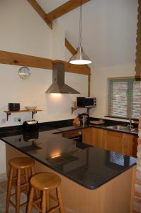 格拉斯顿伯里金银花农场度假屋的厨房配有带2张凳子的大型黑色台面