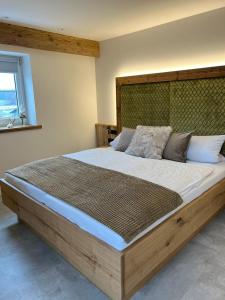 苏尔茨巴赫-罗森贝格Hotel Gasthof zum Wulfen的一间卧室配有一张大床和木制床头板