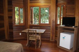 卡内拉Pousada Floresta Negra的客房设有桌子、电视和窗户。