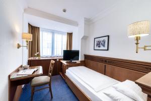 因斯布鲁克蒙德施恩酒店的酒店客房配有一张床、一张书桌和一台电视。