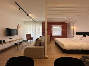 卡兰巴卡Centro Urban Suites的一间卧室配有一张床、一张沙发和一台电视。