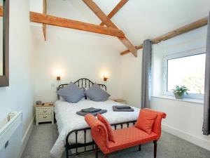 廷塔杰尔Mews Cottage的一间卧室配有一张床和一张红色椅子