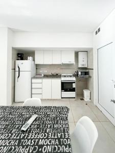 圣达菲Departamento de un dormitorio - PB的厨房配有白色家电和桌椅