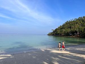 沙拉海滩Green Papaya Beach Resort, Koh Phangan的两人在海边散步