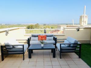 韦尔瓦Ático de lujo - Luxury Penthouse的天井配有沙发、两把椅子和一张桌子