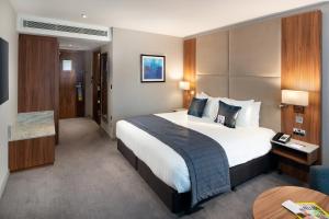 希灵登伦敦希思罗机场皇冠假日酒店第四航站楼店的酒店客房设有一张大床和一张桌子。