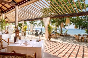 高兰Lanta Palace Beach Resort & Spa - Adult Only的海滩上的餐厅,配有桌椅